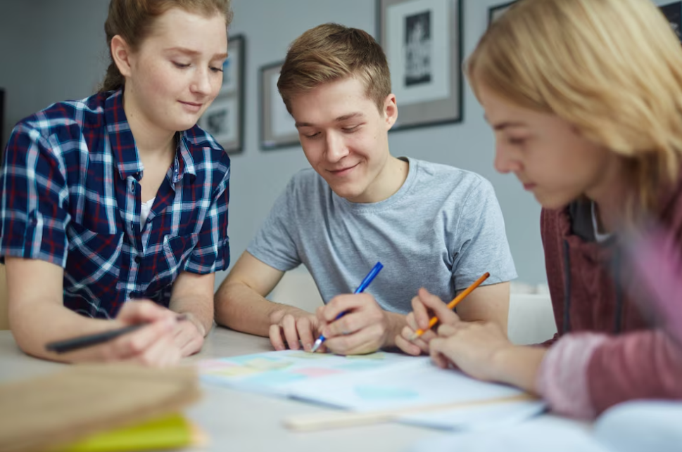 two students take notes, and one girl in shirt observes